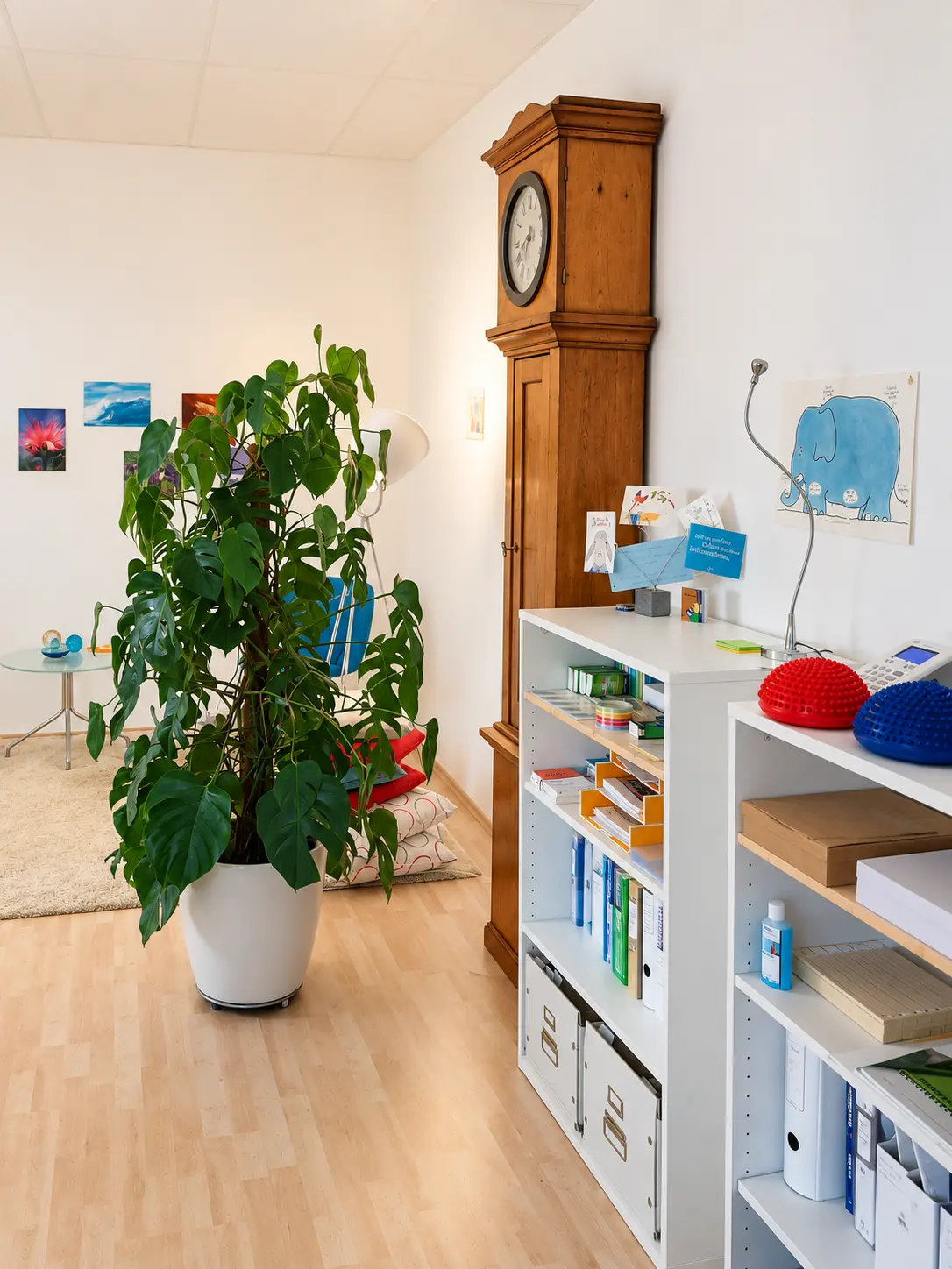Monstera in weißem Topf vor einer alten Standuhr in der Praxis